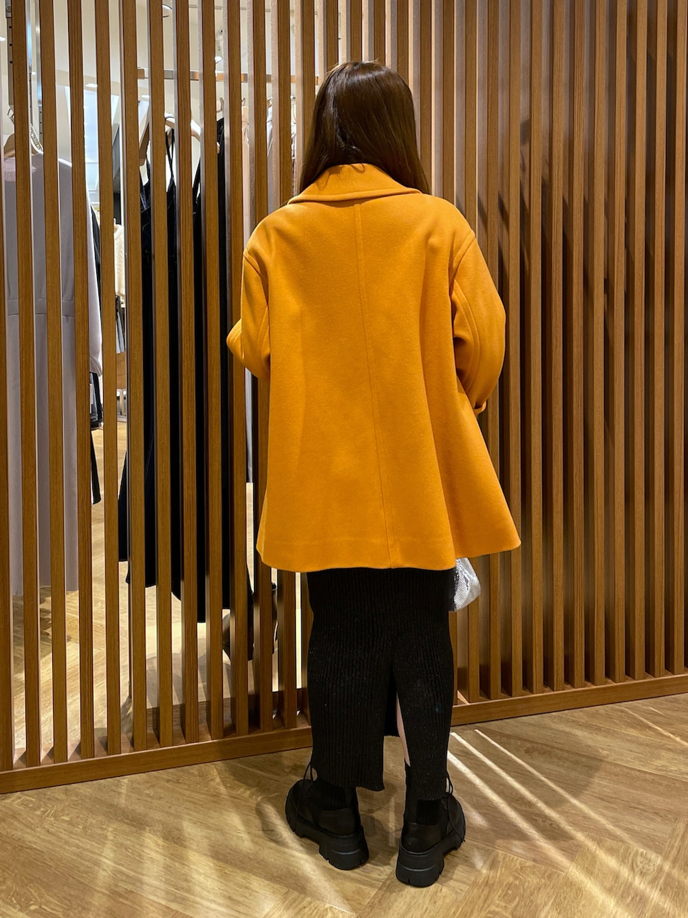 ホワイト系のニット/セーター、ブラック系のスカート、オレンジ系のピーコートを着用したレディースの冬コーディネートの3枚目の写真