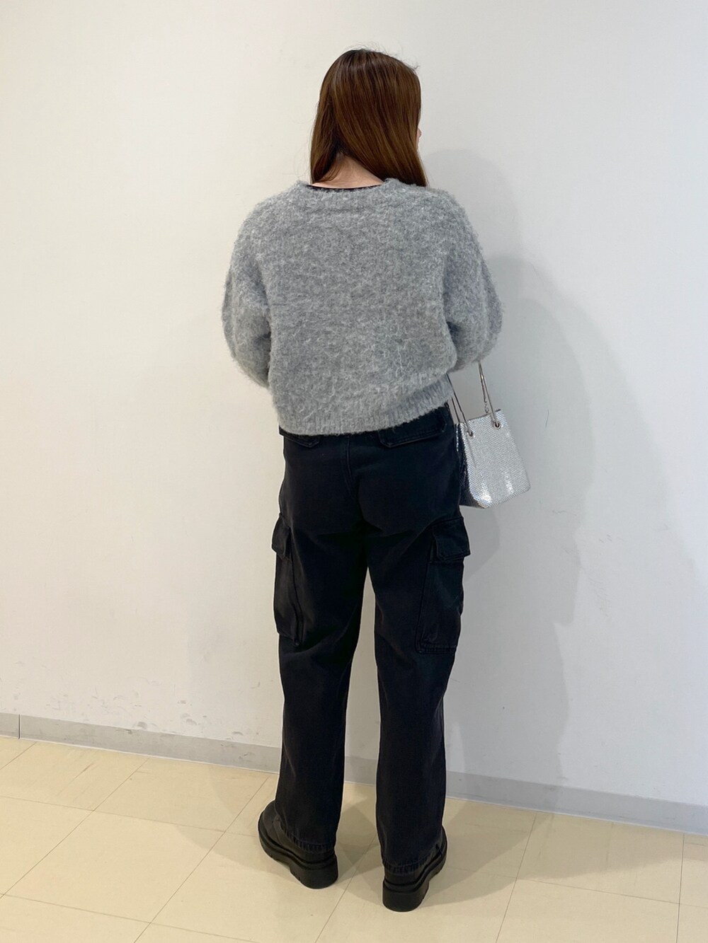 ブラック系のデニムパンツ、グレー系のニット/セーター、シルバー系のハンドバッグを着用したレディースの冬コーディネートの3枚目の写真