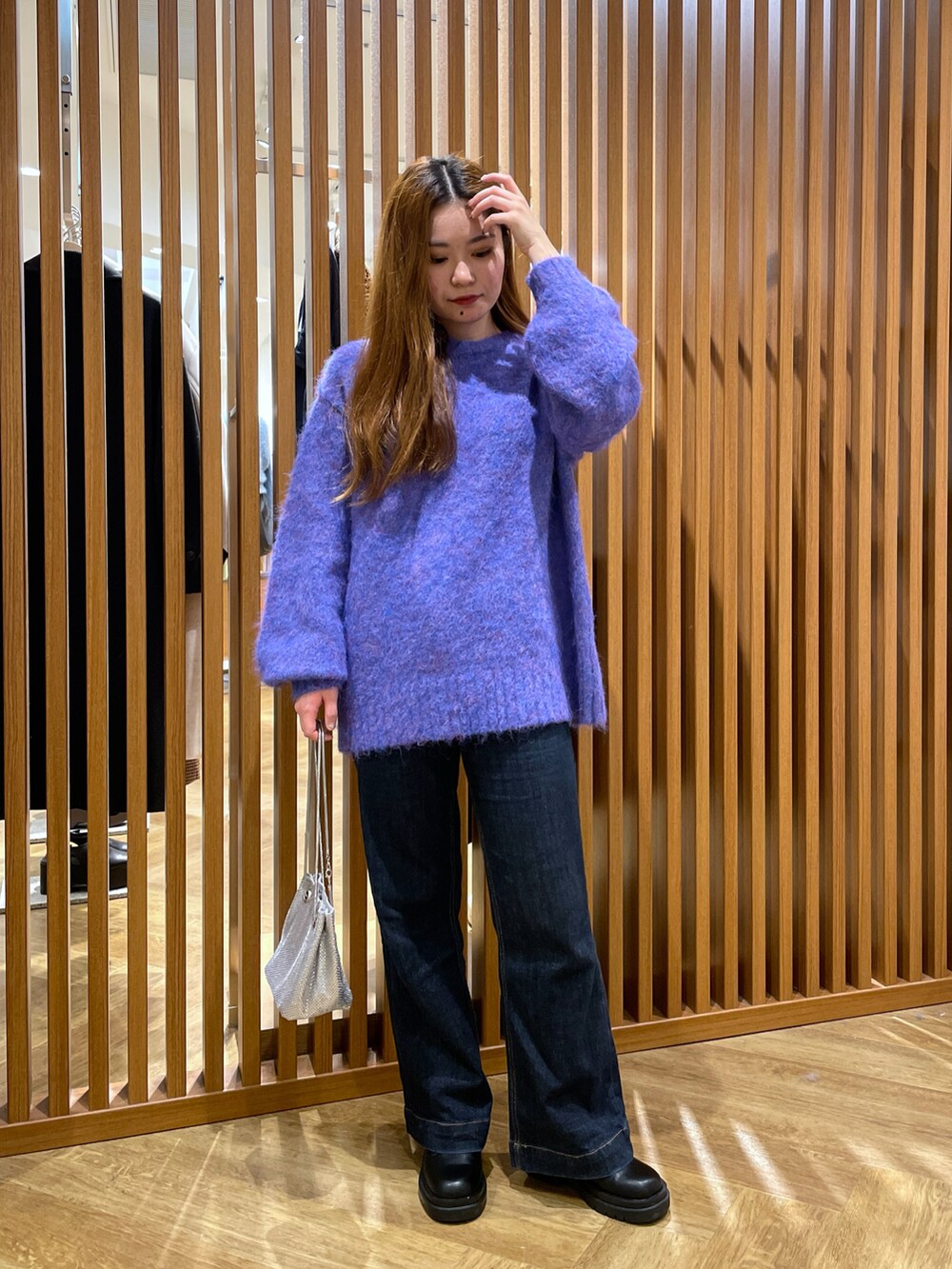 ブルー系のニット/セーター、シルバー系のハンドバッグ、ブルー系のデニムパンツを着用したレディースの冬コーディネートの3枚目の写真