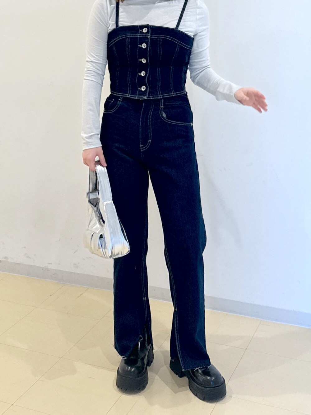 ブルー系のベスト、ブルー系のデニムパンツ、シルバー系のショルダーバッグを着用したレディースの冬コーディネートの3枚目の写真