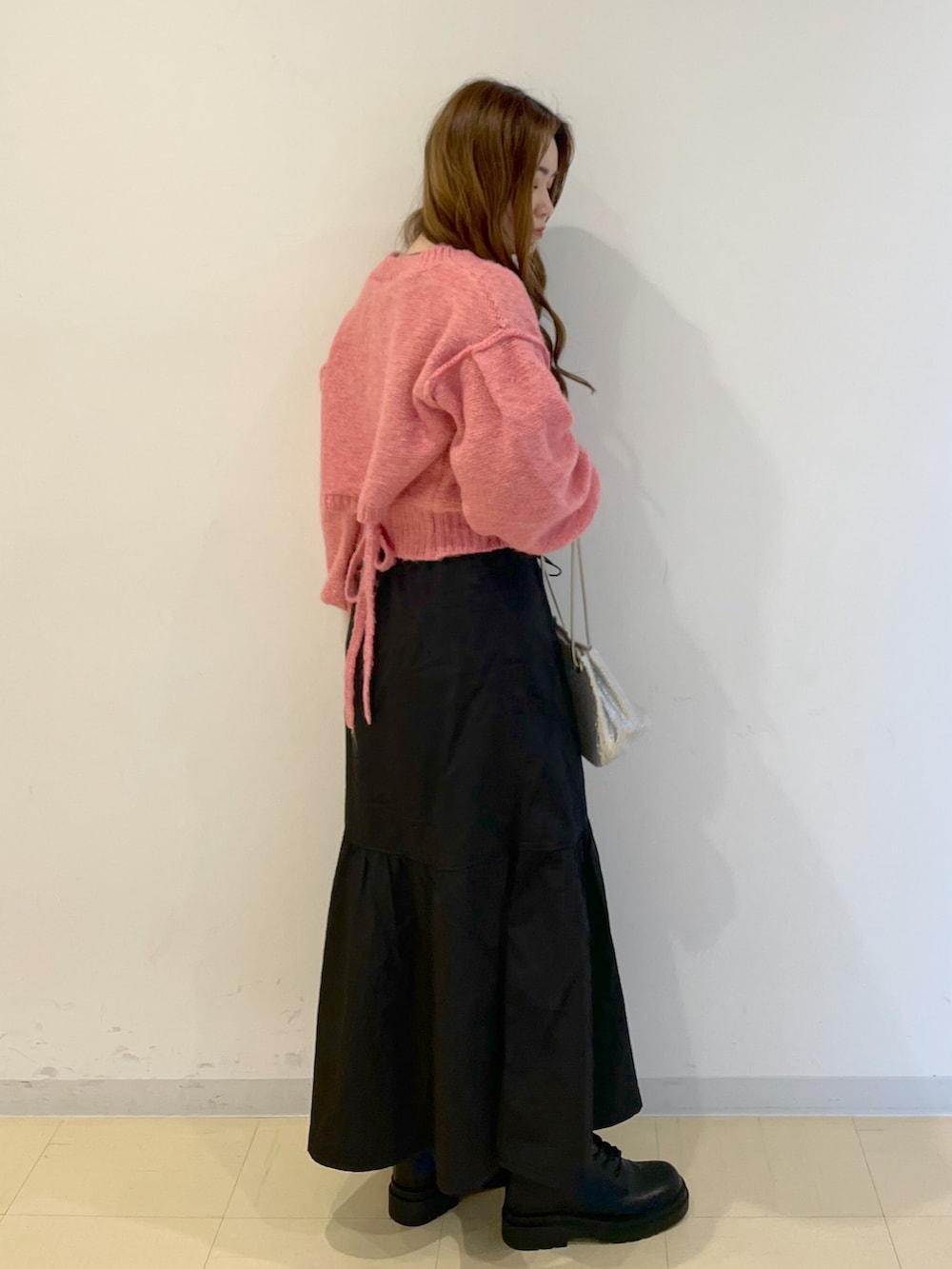 ピンク系のニット/セーター、シルバー系のハンドバッグ、ブラック系のスカートを着用したレディースの冬コーディネートの2枚目の写真