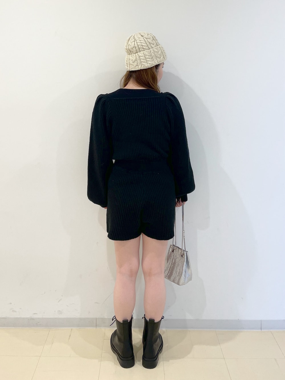 ブラック系のワンピース、シルバー系のハンドバッグ、ブラック系のブーツを着用したレディースの冬コーディネートの2枚目の写真