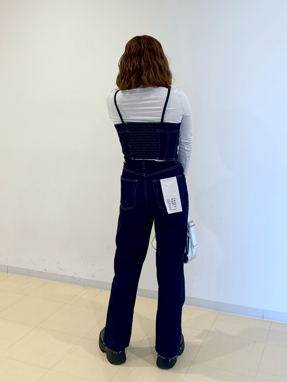 ブルー系のベスト、ブルー系のデニムパンツ、シルバー系のショルダーバッグを着用したレディースの冬コーディネートの2枚目の写真