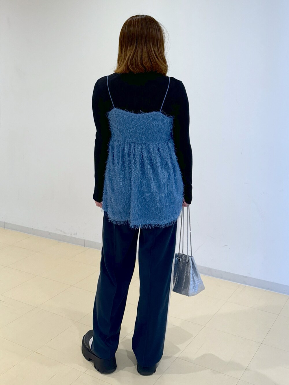 ブラック系のニット/セーター、ブルー系のシャツ/ブラウス、シルバー系のハンドバッグを着用したレディースの冬コーディネートの3枚目の写真