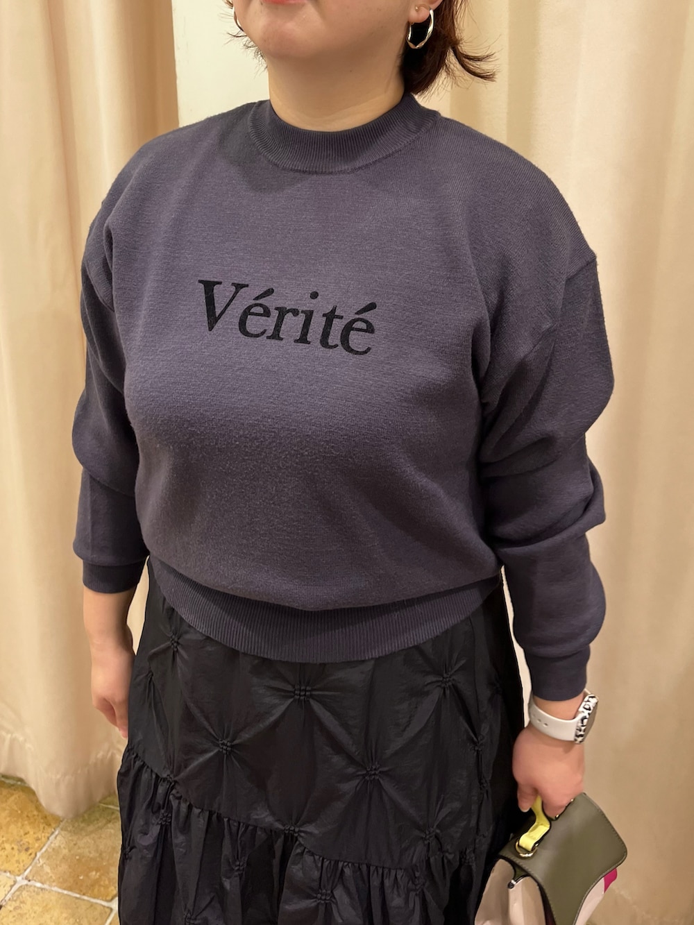 グレー系のニット/セーター、ブラック系のスカート、ピンク系のハンドバッグを着用したレディースの冬コーディネートの2枚目の写真