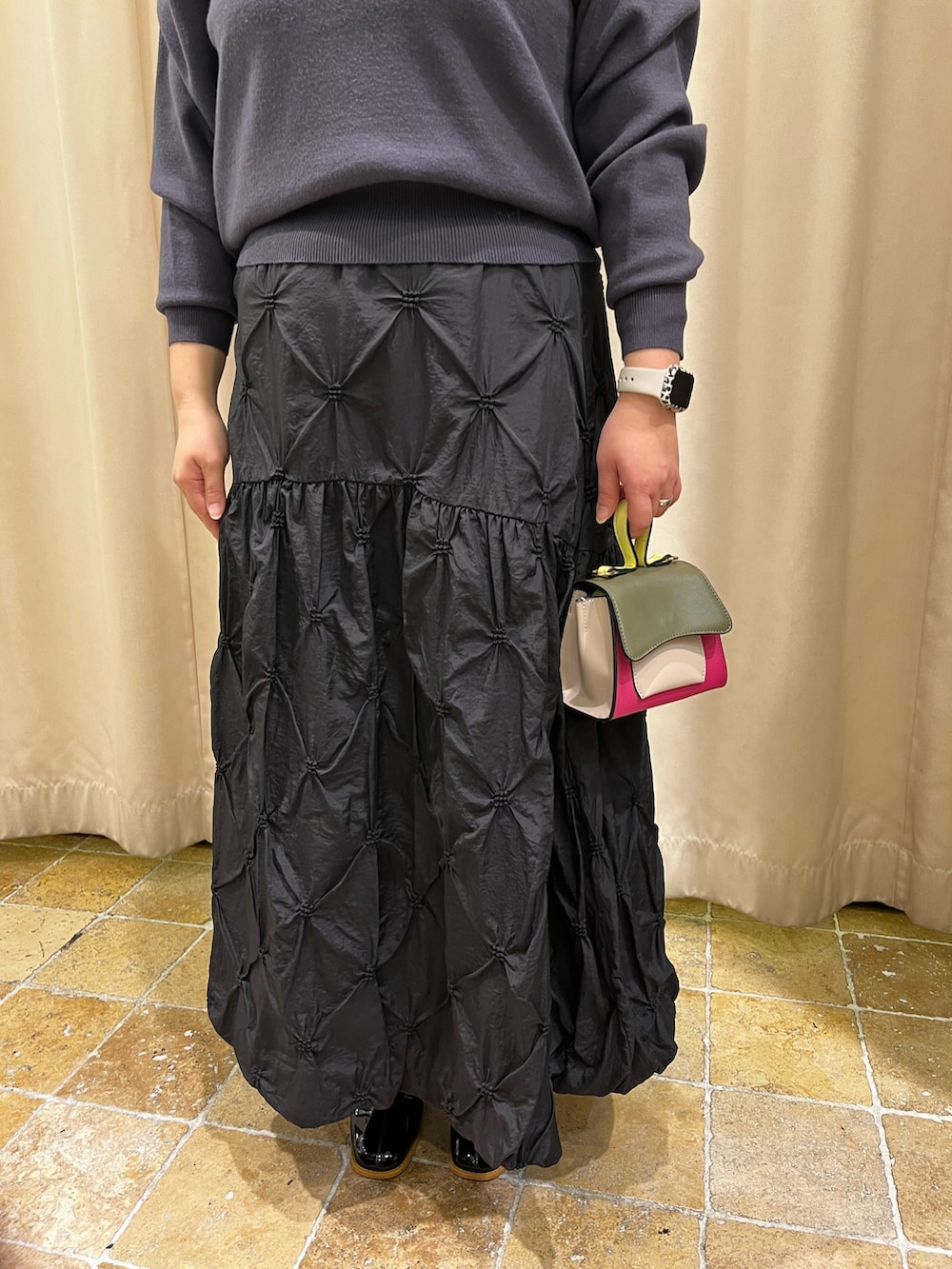 グレー系のニット/セーター、ブラック系のスカート、ピンク系のハンドバッグを着用したレディースの冬コーディネートの3枚目の写真