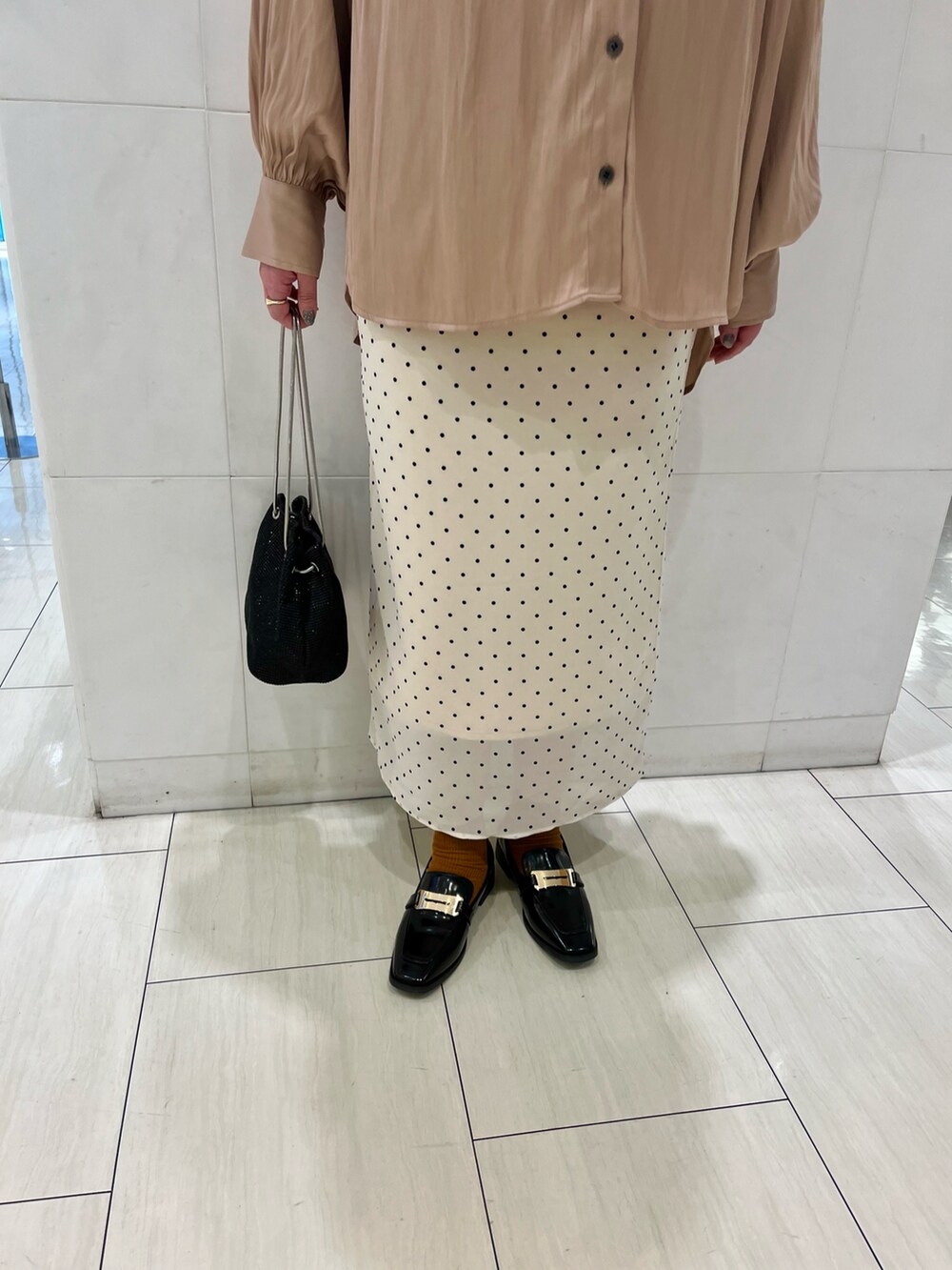 ベージュ系のシャツ/ブラウス、ベージュ系のスカート、ブラック系のローファーを着用したレディースの春コーディネートの4枚目の写真