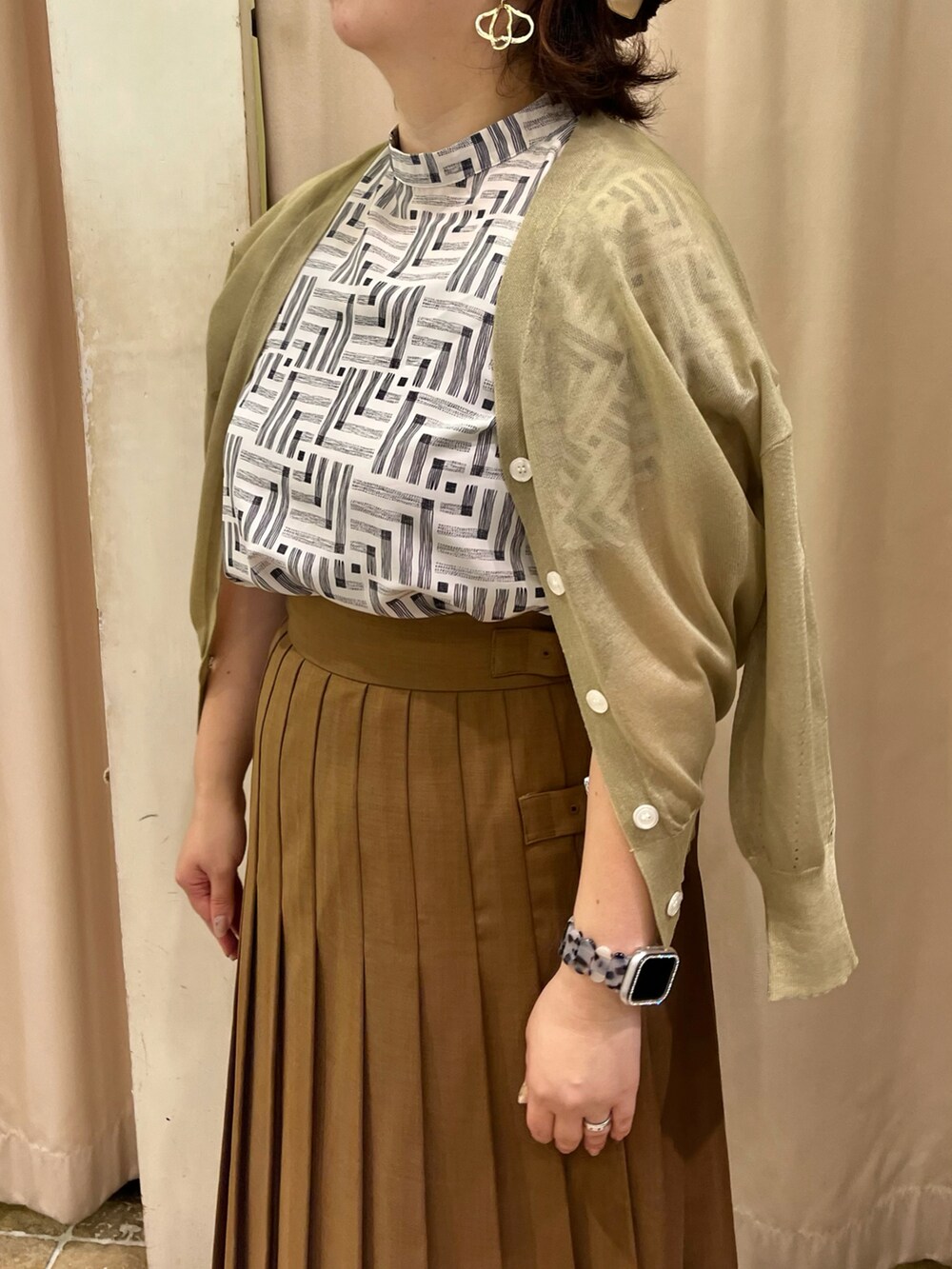 グリーン系のカーディガン/ボレロ、ホワイト系のシャツ/ブラウス、ブラウン系のスカートを着用したレディースの夏コーディネートの2枚目の写真