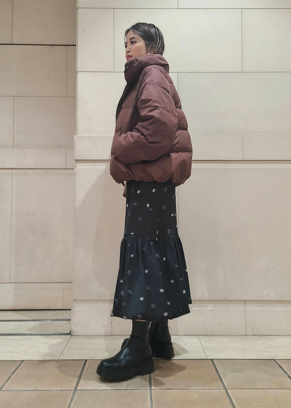 ブラウン系のダウンジャケット/コート、ブラック系のショルダーバッグ、イエロー系のニット/セーターを着用したレディースの冬コーディネートの2枚目の写真