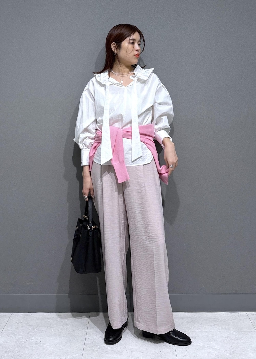 ブラック系のショルダーバッグ、ブラック系のローファー、ピンク系のカーディガン/ボレロを着用したレディースの春コーディネートの2枚目の写真