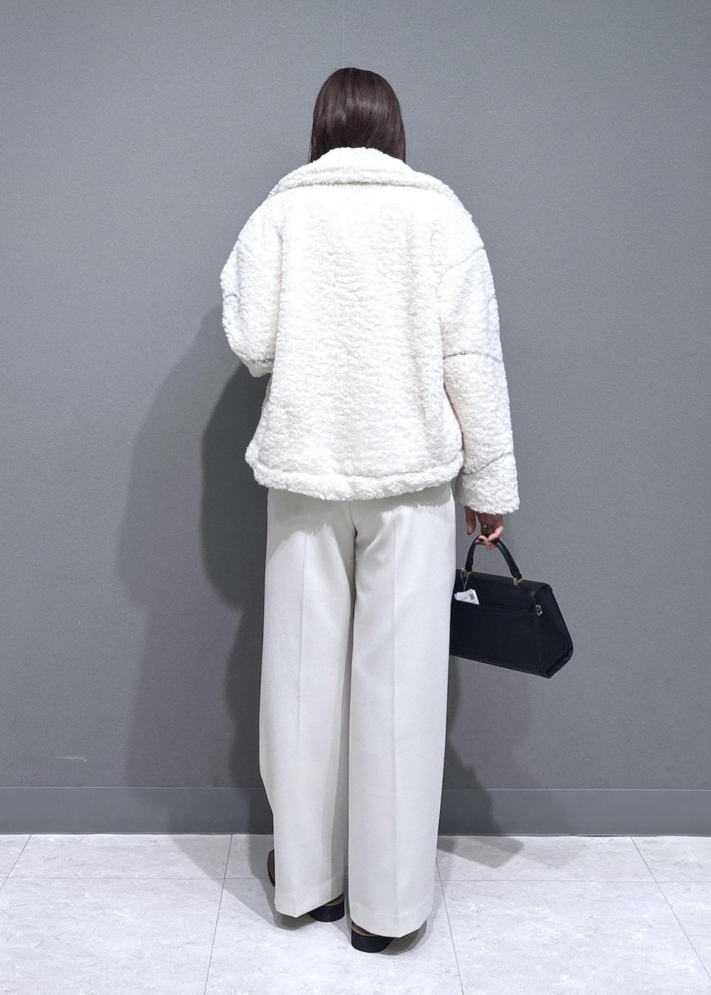 ブラック系のローファー、ホワイト系のブルゾン、ブラック系のハンドバッグを着用したレディースの冬コーディネートの2枚目の写真