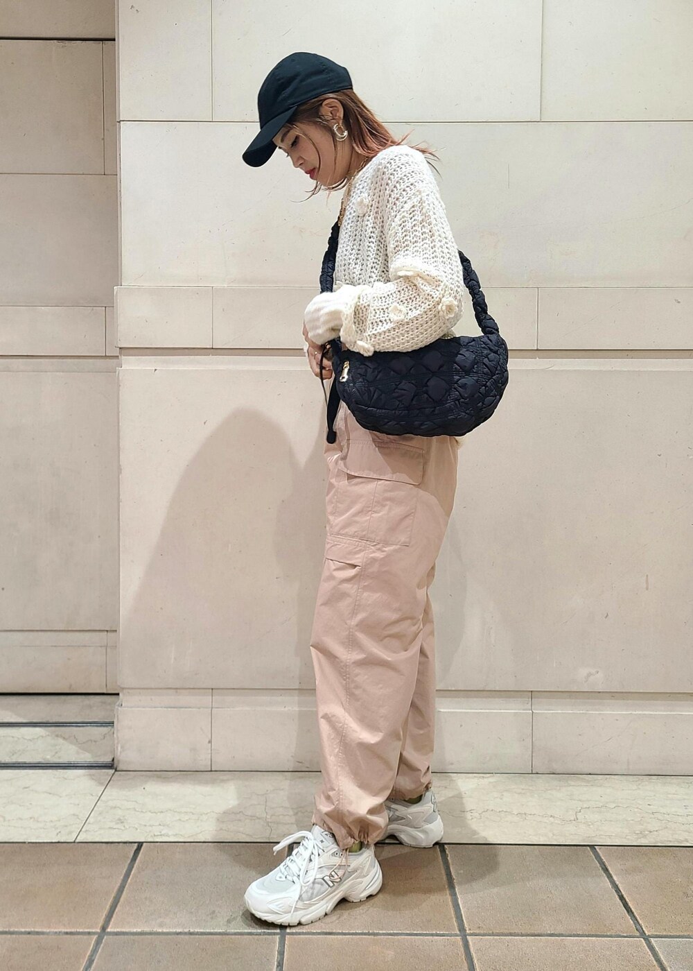 ホワイト系のニット/セーター、オレンジ系のカーゴパンツ、ブラック系のショルダーバッグを着用したレディースの冬コーディネートの2枚目の写真