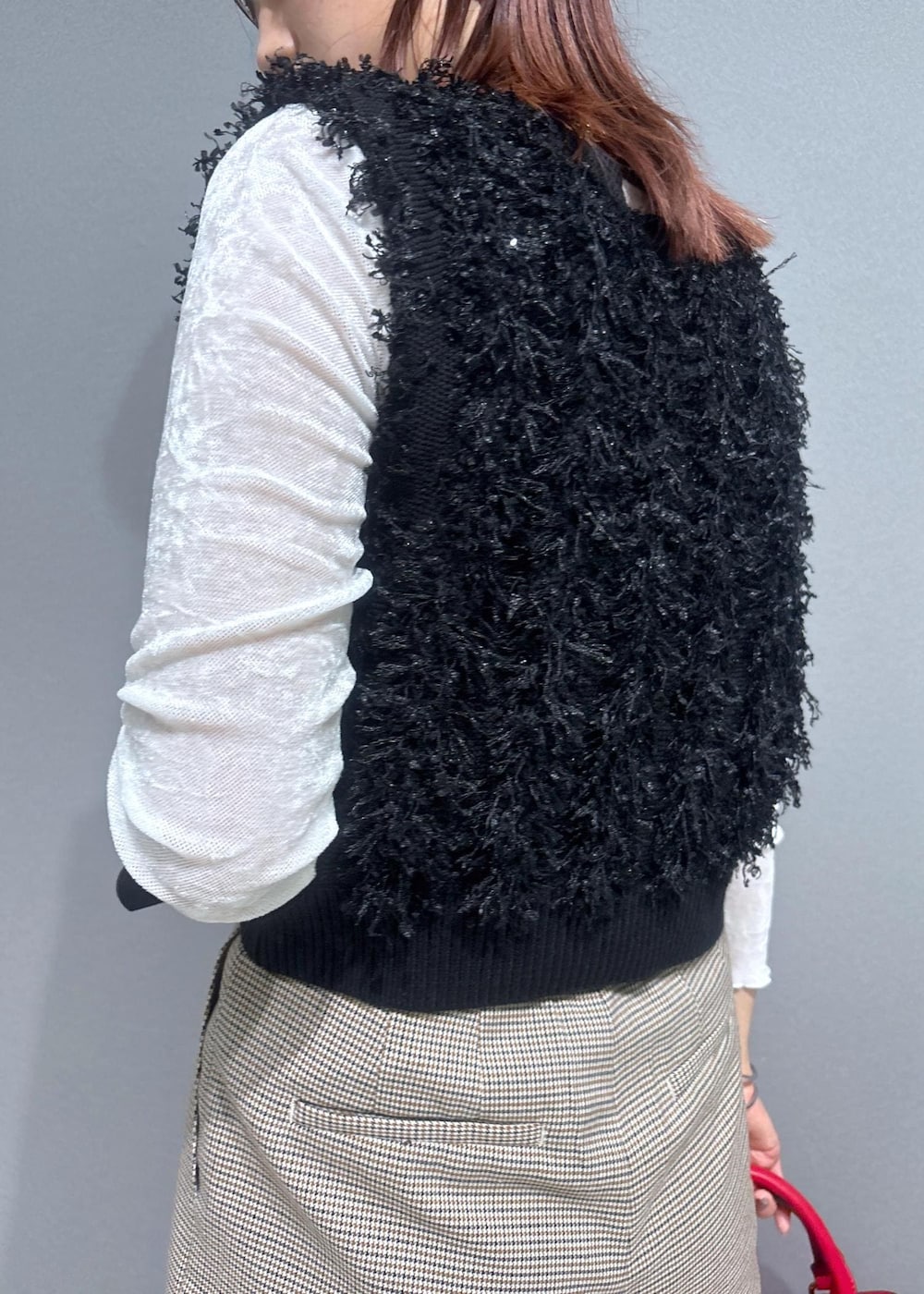 ベージュ系のスラックス、レッド系のボストンバッグ、ブラック系のベストを着用したレディースの秋コーディネートの5枚目の写真