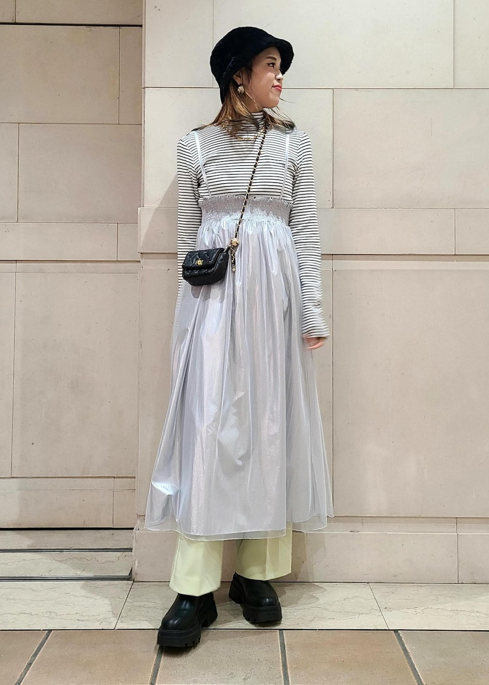 ブラック系のショルダーバッグ、ホワイト系のニット/セーター、グリーン系のスラックスを着用したレディースの冬コーディネートの2枚目の写真