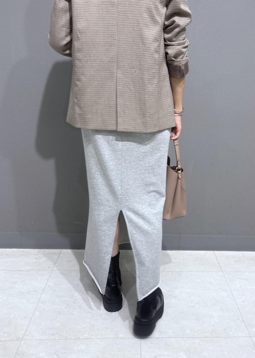 ベージュ系のテーラードジャケット、グレー系のスカート、ホワイト系のベストを着用したレディースの秋コーディネートの8枚目の写真