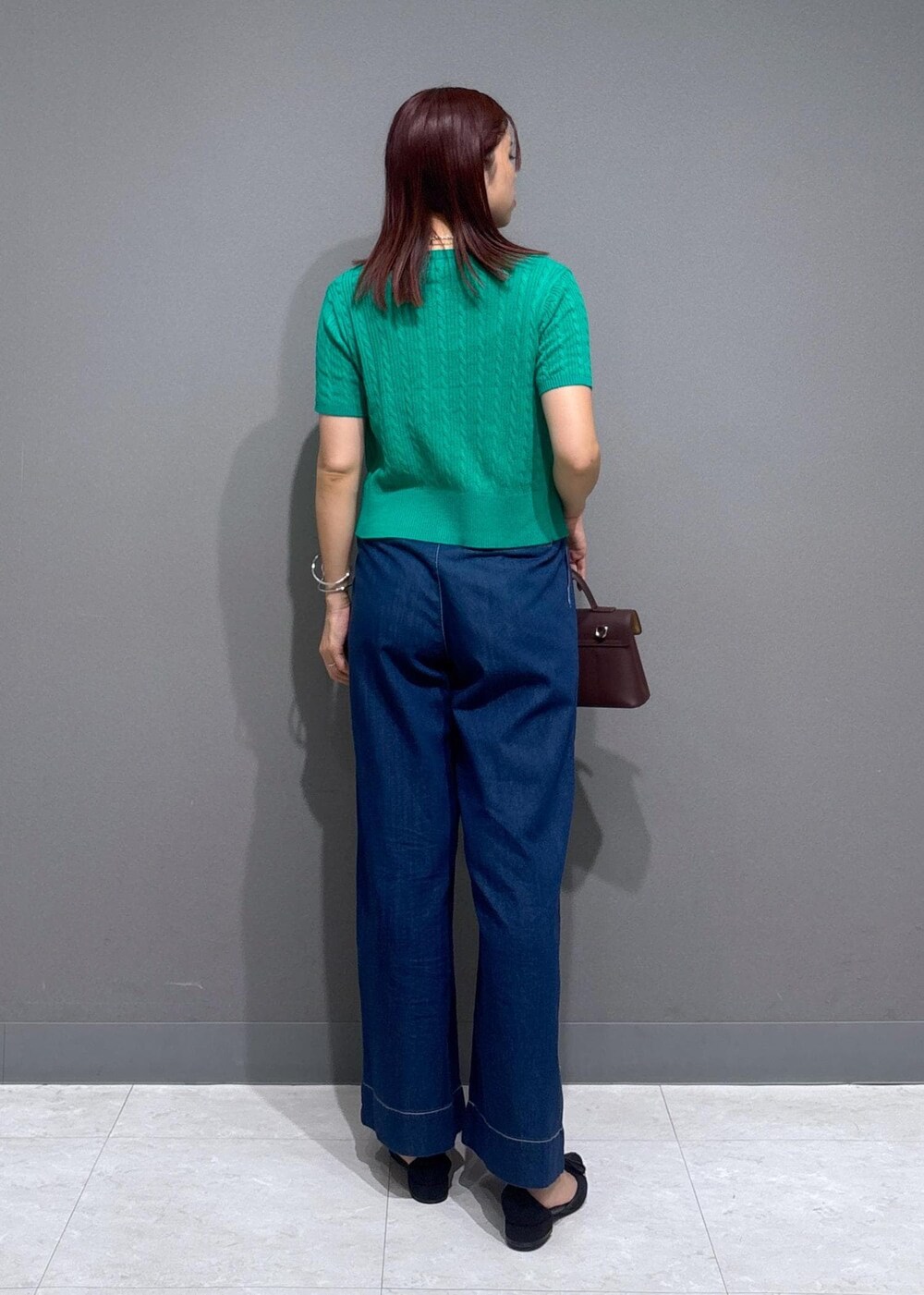 ブラウン系のショルダーバッグ、グレー系のタンクトップ、ブルー系のデニムパンツを着用したレディースの夏コーディネートの2枚目の写真