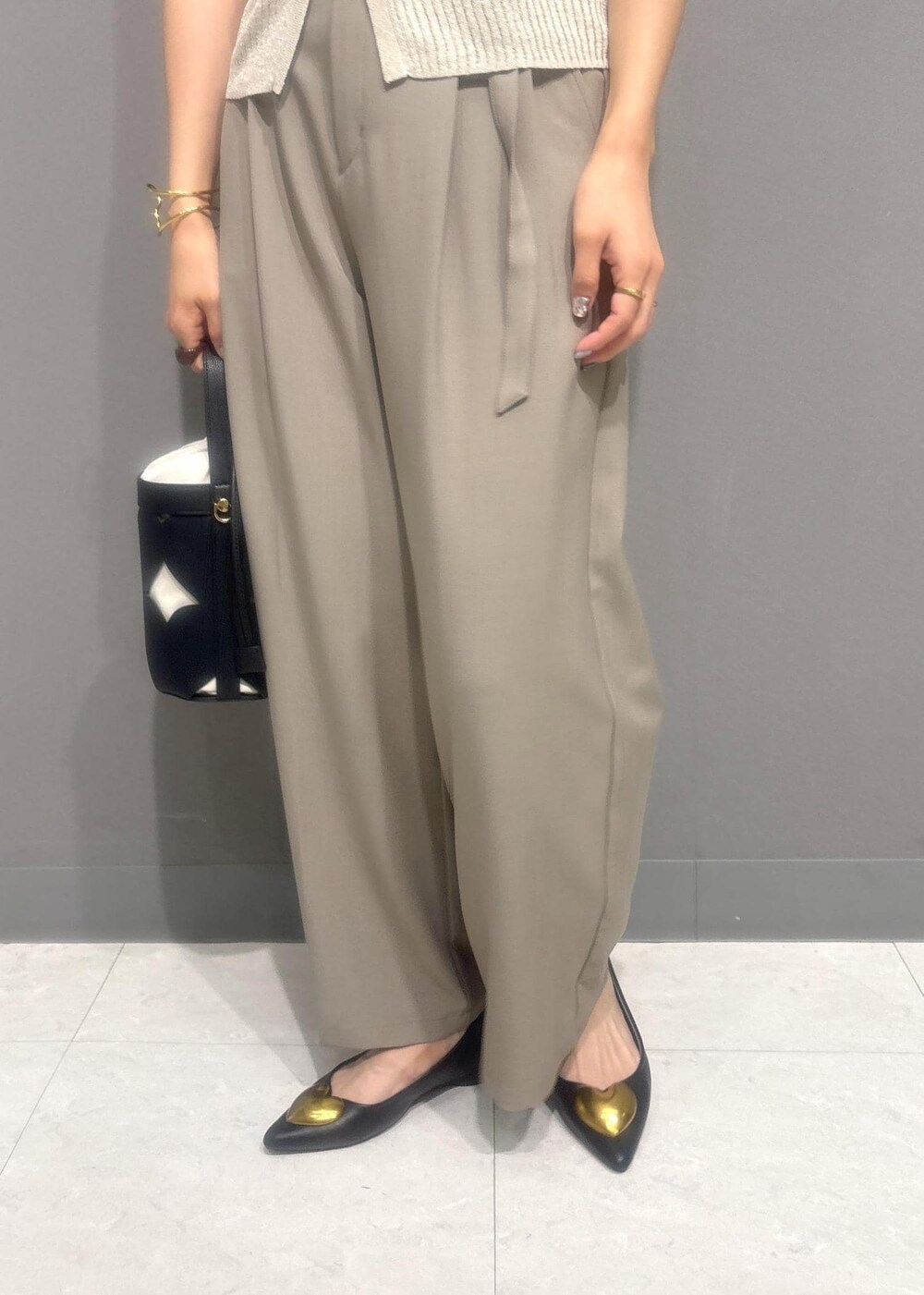 ブラック系のバレエシューズ、ベージュ系のスラックス、ホワイト系のカーディガン/ボレロを着用したレディースの夏コーディネートの7枚目の写真