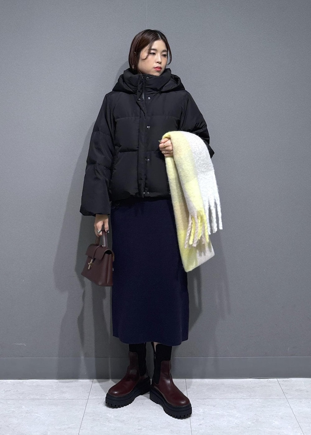 ブラウン系のショルダーバッグ、ブラウン系のブーツ、ブルー系のワンピースを着用したレディースの冬コーディネートの2枚目の写真