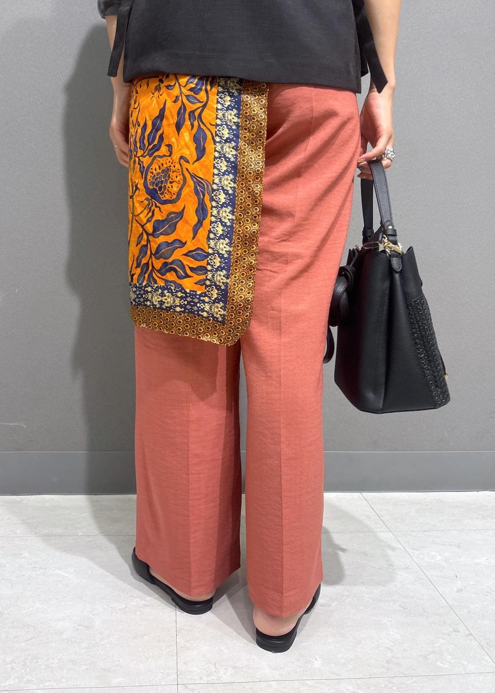 ブラック系のサンダル、ホワイト系のニット/セーター、オレンジ系のスラックスを着用したレディースの夏コーディネートの8枚目の写真