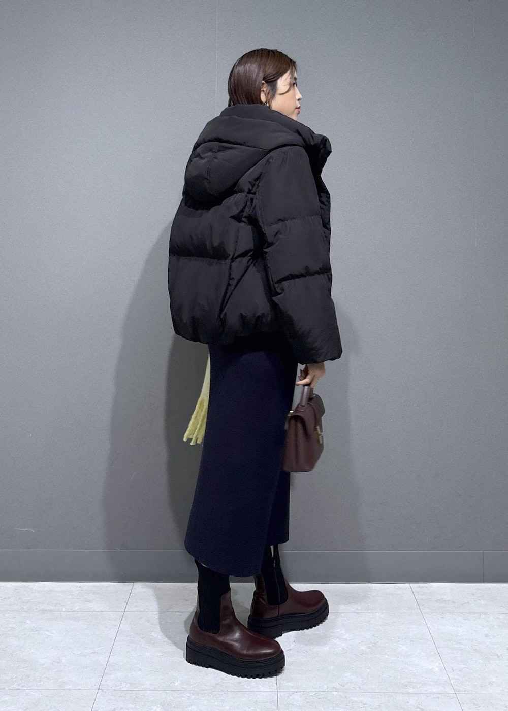 ブラウン系のショルダーバッグ、ブラウン系のブーツ、ブルー系のワンピースを着用したレディースの冬コーディネートの3枚目の写真