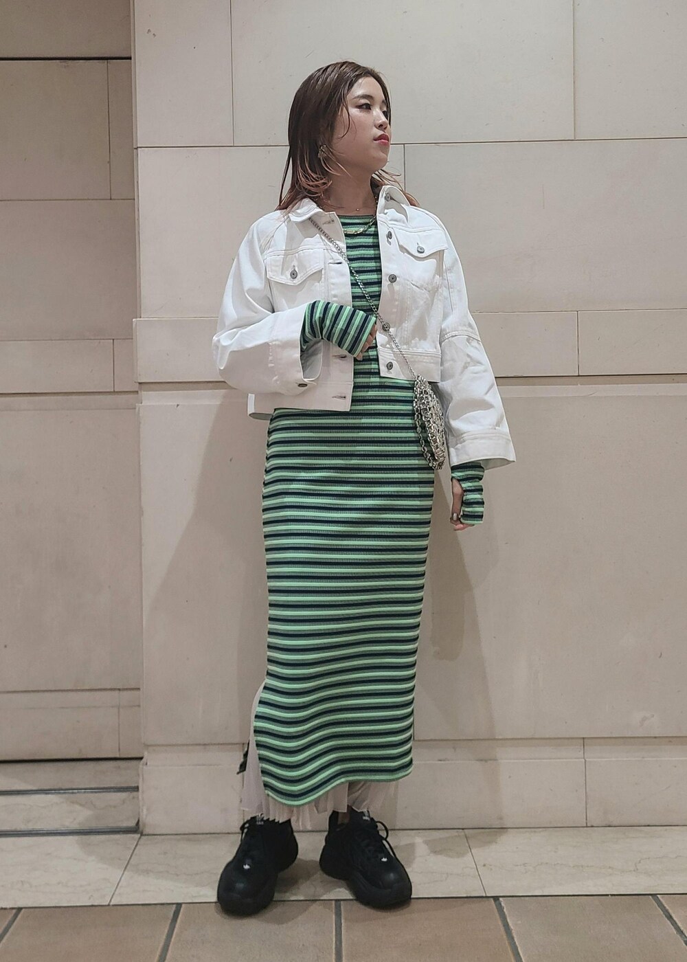 ホワイト系のデニムジャケット、シルバー系のショルダーバッグ、ホワイト系のスカートを着用したレディースの冬コーディネートの2枚目の写真