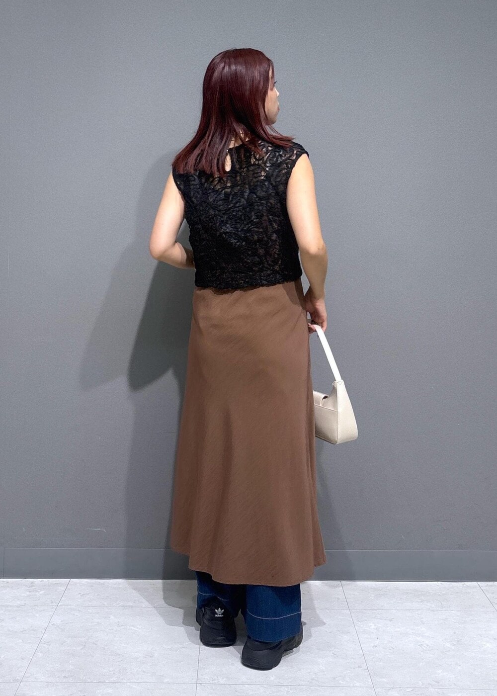 グレー系のタンクトップ、ブルー系のデニムパンツ、ホワイト系のショルダーバッグを着用したレディースの夏コーディネートの4枚目の写真