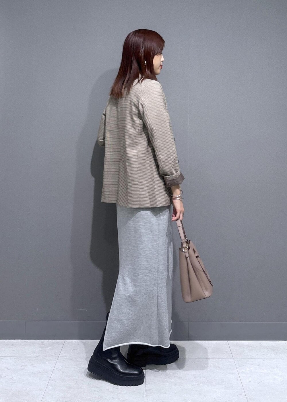 ベージュ系のテーラードジャケット、グレー系のスカート、ホワイト系のベストを着用したレディースの秋コーディネートの2枚目の写真