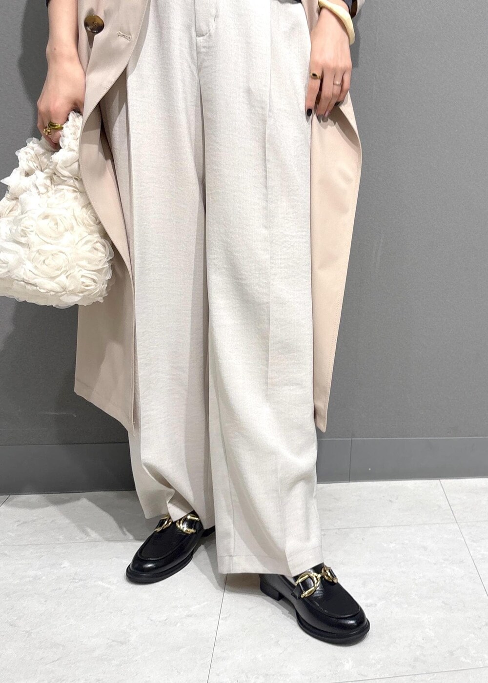 ブラック系のローファー、ブラック系のニット/セーター、ベージュ系のトレンチコートを着用したレディースの春コーディネートの6枚目の写真