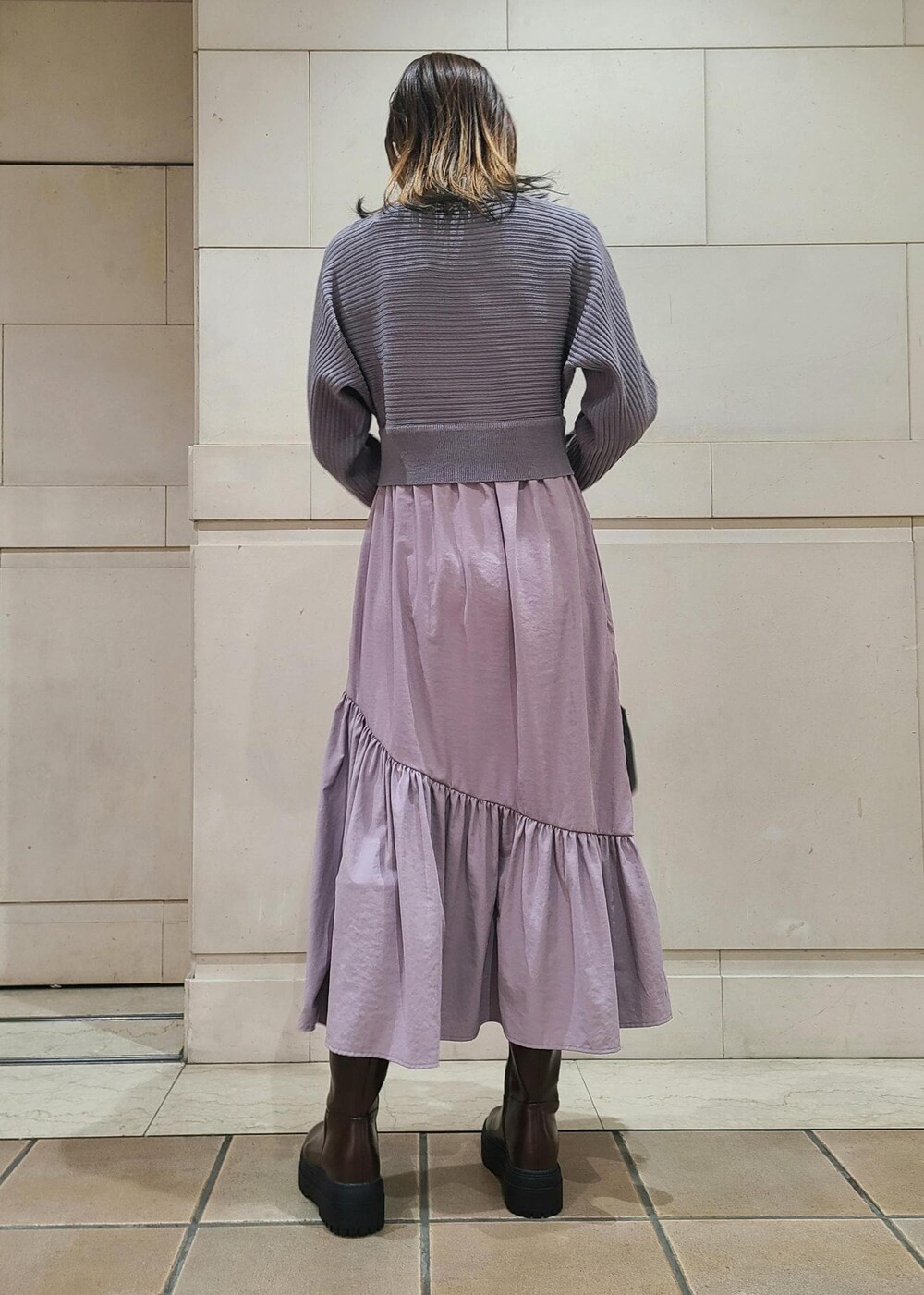 ブラック系のショルダーバッグ、ブラウン系のブーツ、パープル系のワンピースを着用したレディースの冬コーディネートの3枚目の写真