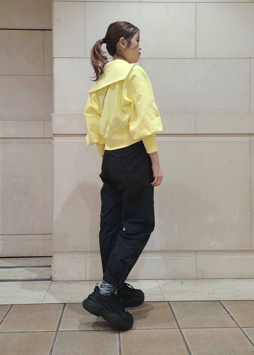 イエロー系のカーディガン/ボレロ、シルバー系のショルダーバッグ、ブラック系のカーゴパンツを着用したレディースの冬コーディネートの2枚目の写真