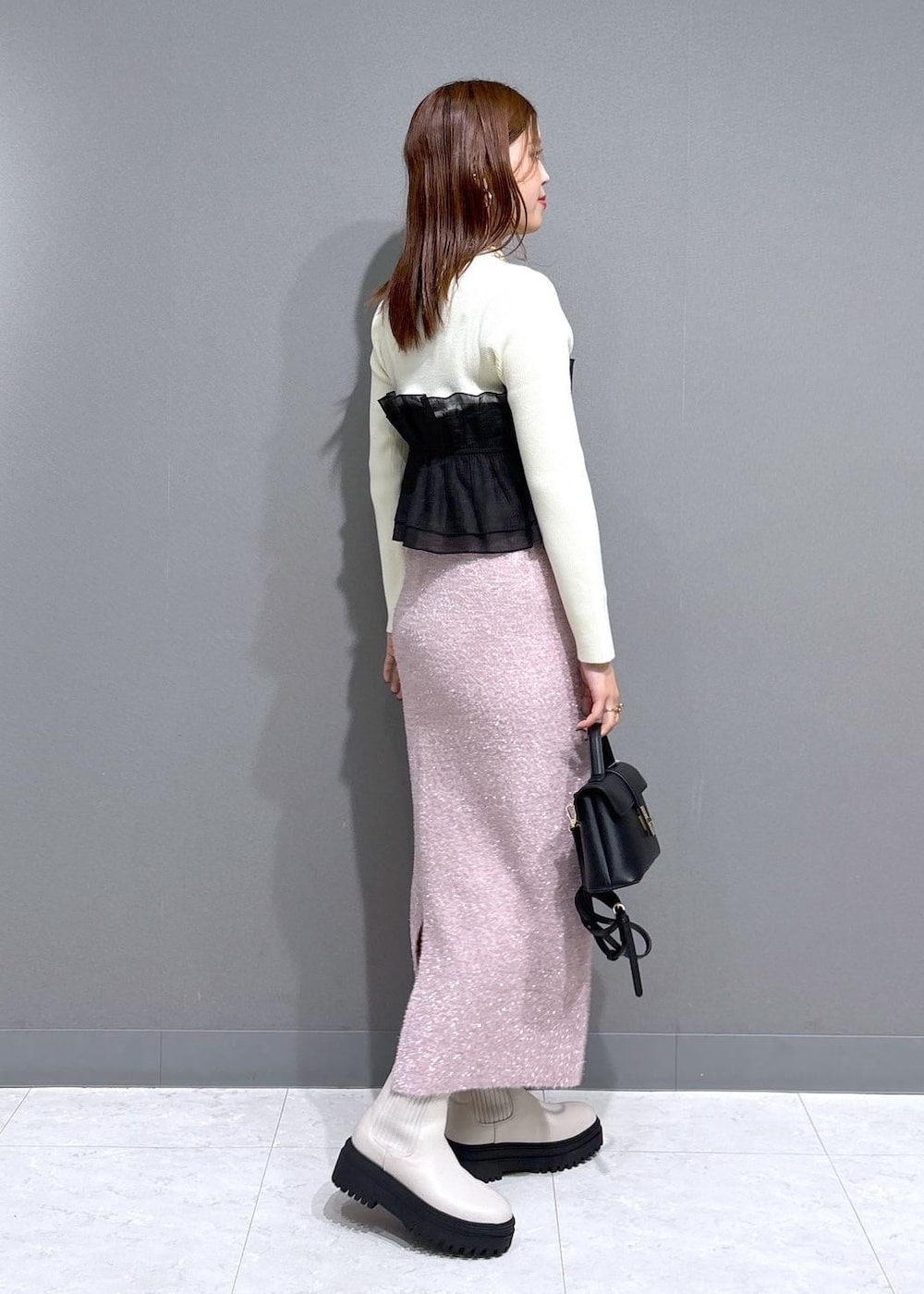 ホワイト系のブーツ、ピンク系のスカート、ホワイト系のニット/セーターを着用したレディースの冬コーディネートの2枚目の写真