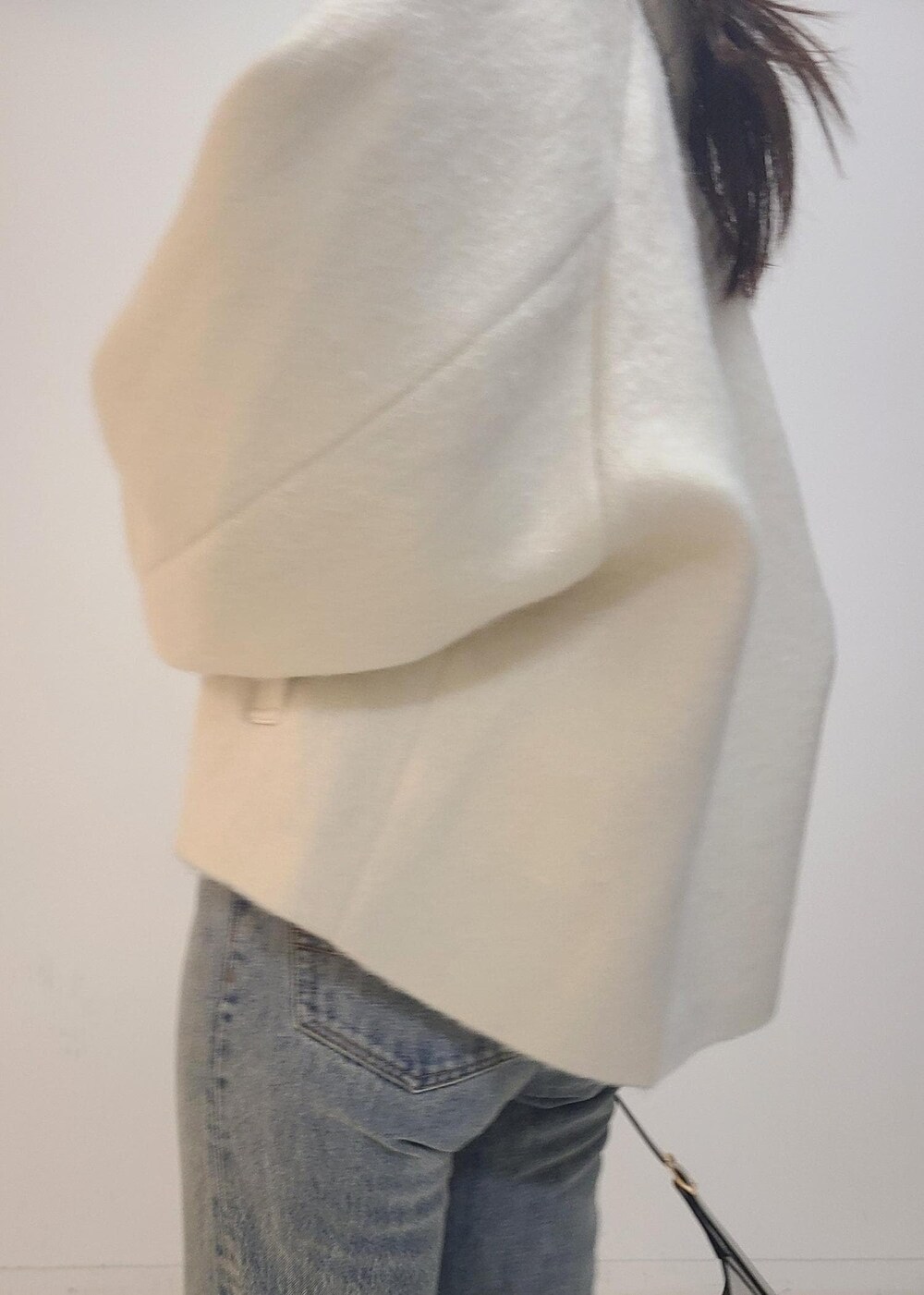 ブルー系のデニムパンツ、ブラック系のブーツ、ホワイト系のハンドバッグを着用したレディースの秋コーディネートの9枚目の写真