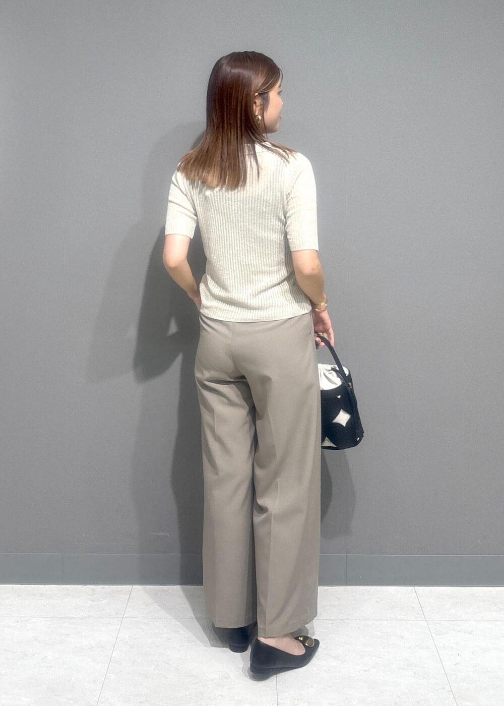 ブラック系のバレエシューズ、ベージュ系のスラックス、ホワイト系のカーディガン/ボレロを着用したレディースの夏コーディネートの3枚目の写真