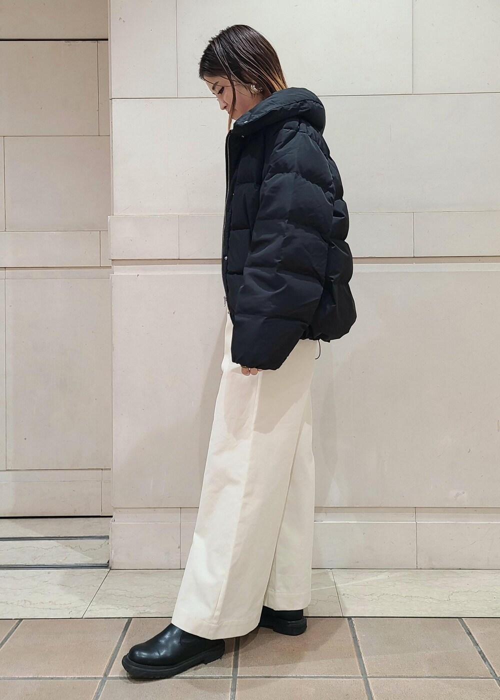 ブラック系のダウンジャケット/コート、グリーン系のハンドバッグ、ホワイト系のスラックスを着用したレディースの冬コーディネートの2枚目の写真