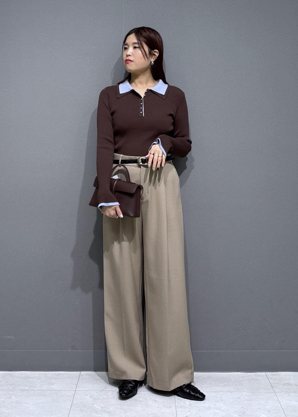 ブラウン系のショルダーバッグ、ベージュ系のスラックス、ブラック系のパンプスを着用したレディースの冬コーディネートの2枚目の写真