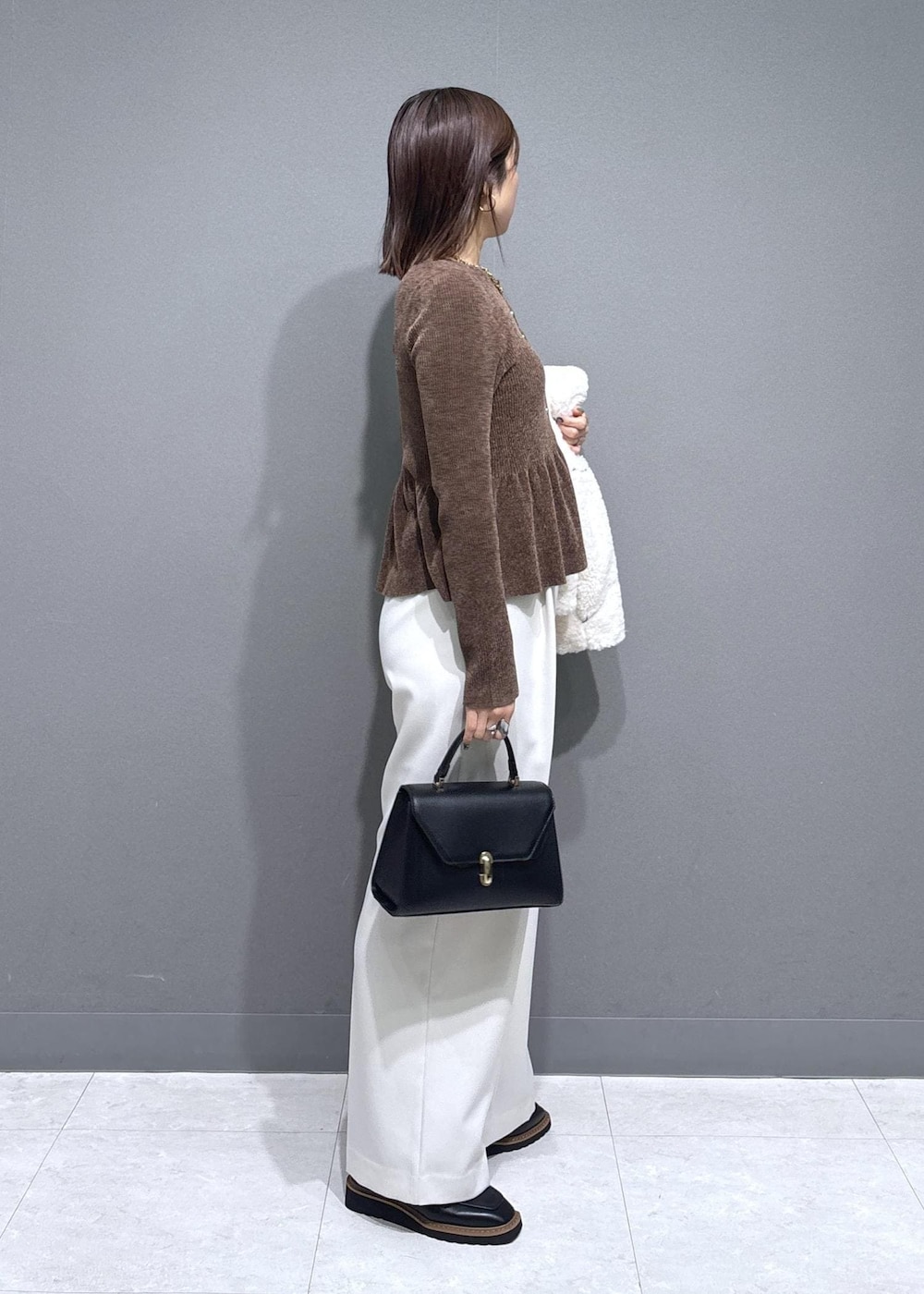 ブラック系のローファー、ホワイト系のブルゾン、ブラック系のハンドバッグを着用したレディースの冬コーディネートの4枚目の写真