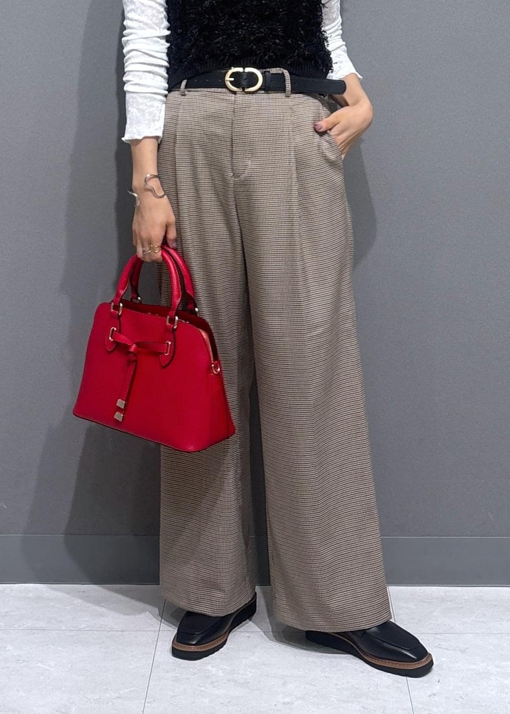 ベージュ系のスラックス、レッド系のボストンバッグ、ブラック系のベストを着用したレディースの秋コーディネートの6枚目の写真