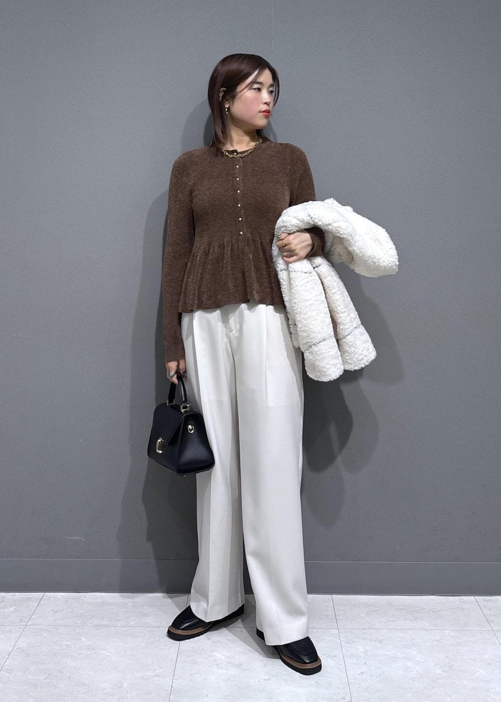 ブラック系のローファー、ホワイト系のブルゾン、ブラック系のハンドバッグを着用したレディースの冬コーディネートの3枚目の写真