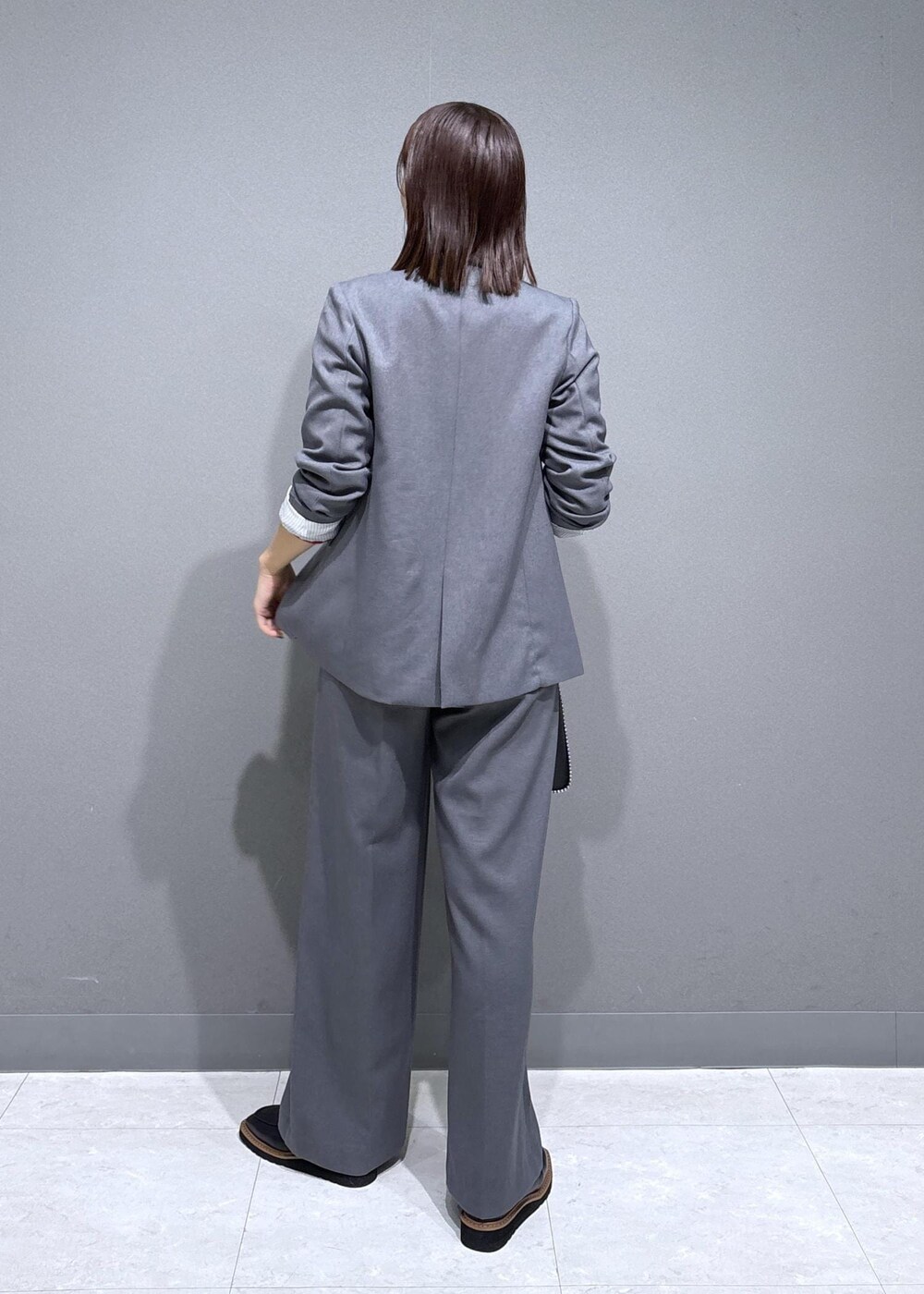 グレー系のスラックス、グレー系のテーラードジャケット、ブラック系のローファーを着用したレディースの秋コーディネートの3枚目の写真