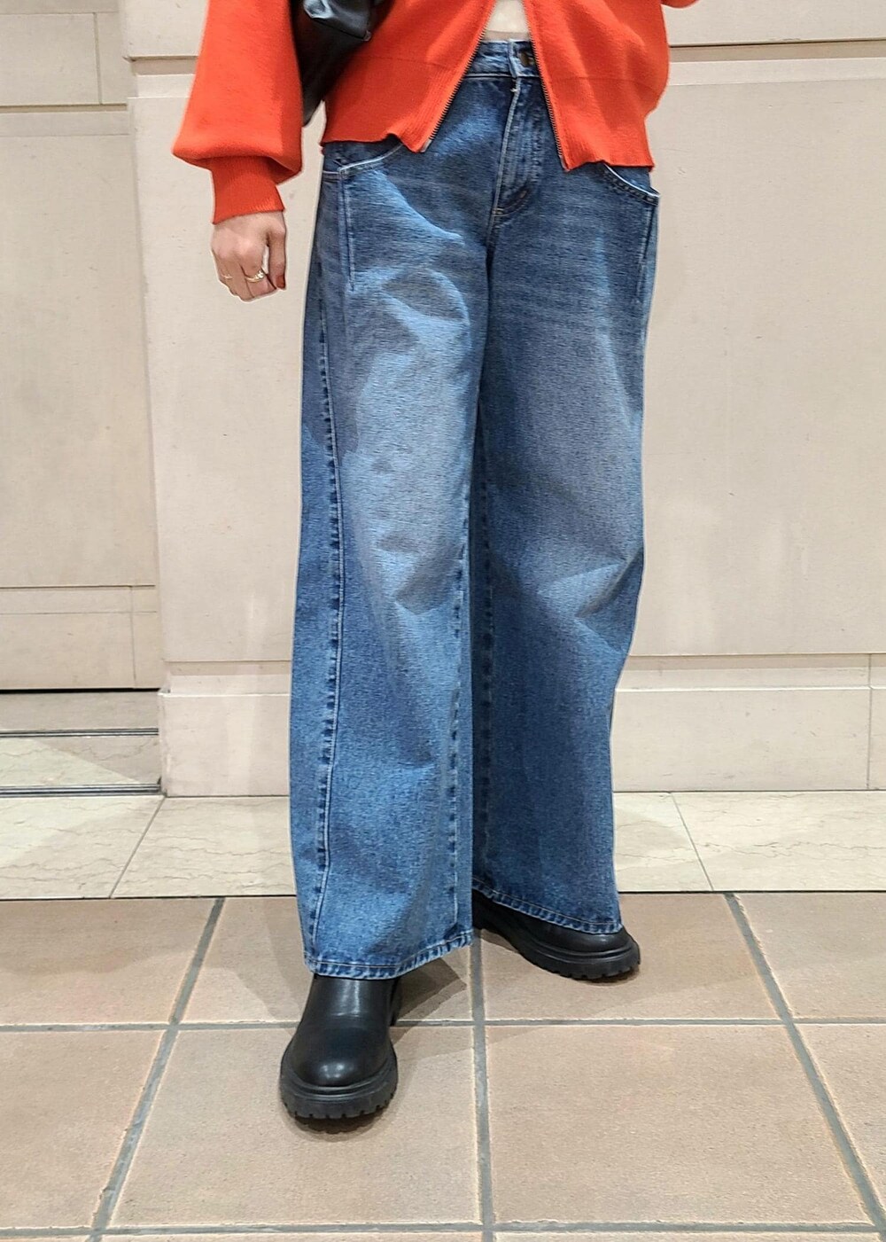 ホワイト系のTシャツ/カットソー、オレンジ系のカーディガン/ボレロ、ブルー系のデニムパンツを着用したレディースの冬コーディネートの3枚目の写真