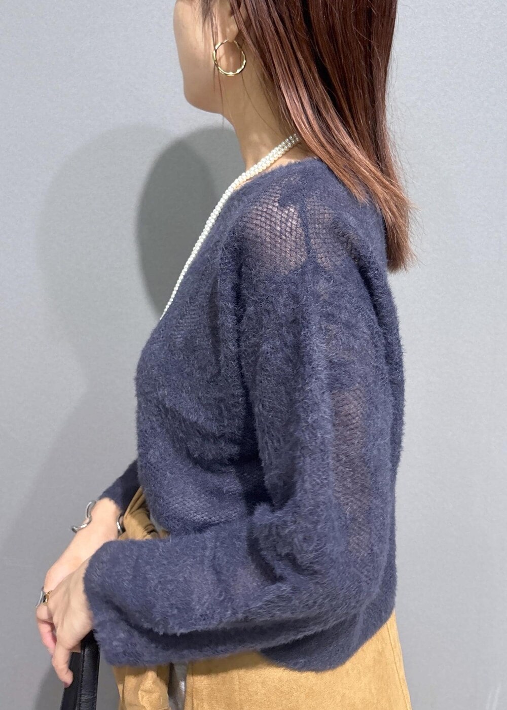 グレー系のニット/セーター、グレー系のスカート、ブラック系のショルダーバッグを着用したレディースの秋コーディネートの5枚目の写真