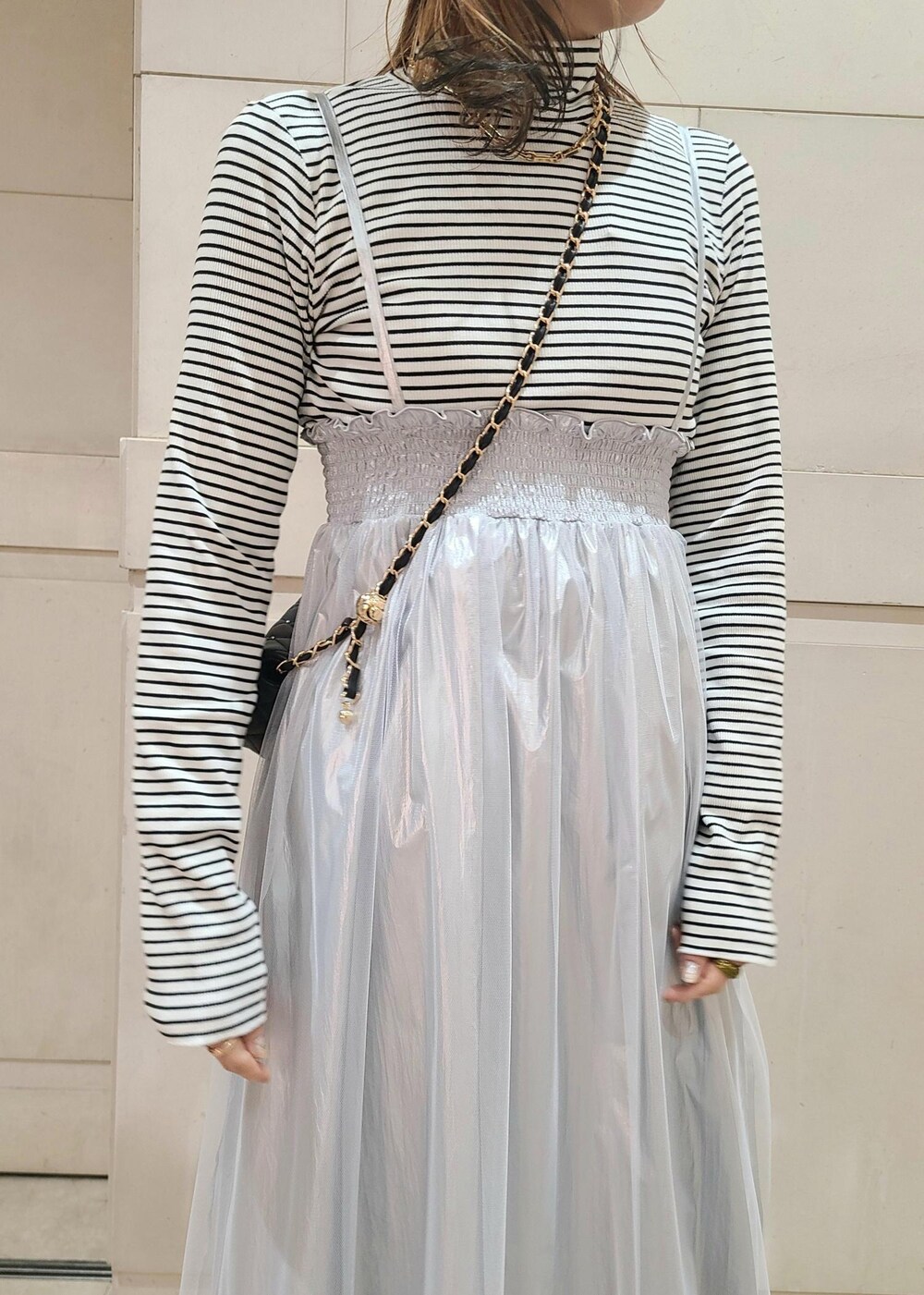 ブラック系のショルダーバッグ、ホワイト系のニット/セーター、グリーン系のスラックスを着用したレディースの冬コーディネートの5枚目の写真