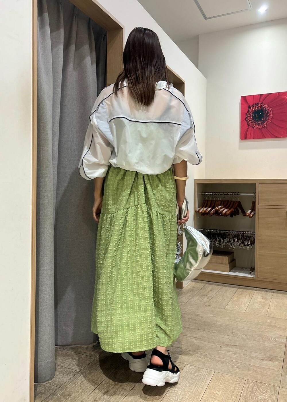 ブラック系のサンダル、グリーン系のワンピース、ホワイト系のブルゾンを着用したレディースの春コーディネートの2枚目の写真