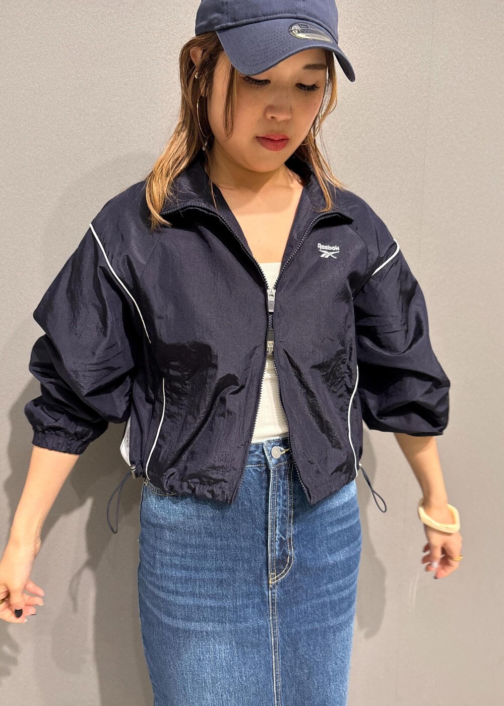 ブルー系のデニムスカート、ブルー系のブルゾン、ベージュ系のトレンチコートを着用したレディースの春コーディネートの4枚目の写真