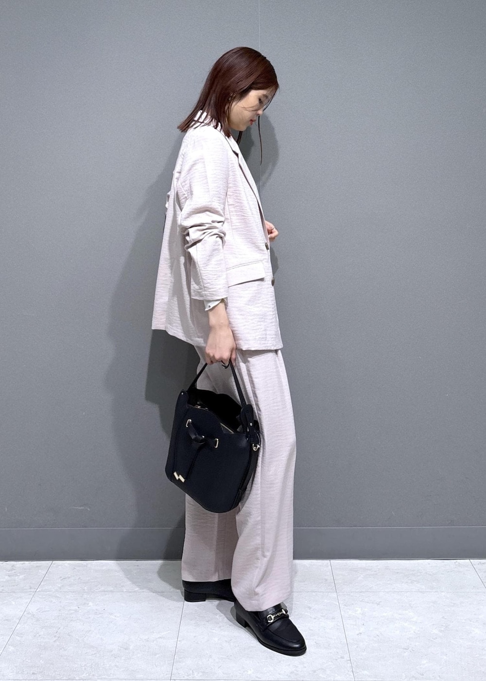 ブラック系のショルダーバッグ、ブラック系のローファー、ホワイト系のカーディガン/ボレロを着用したレディースの春コーディネートの2枚目の写真
