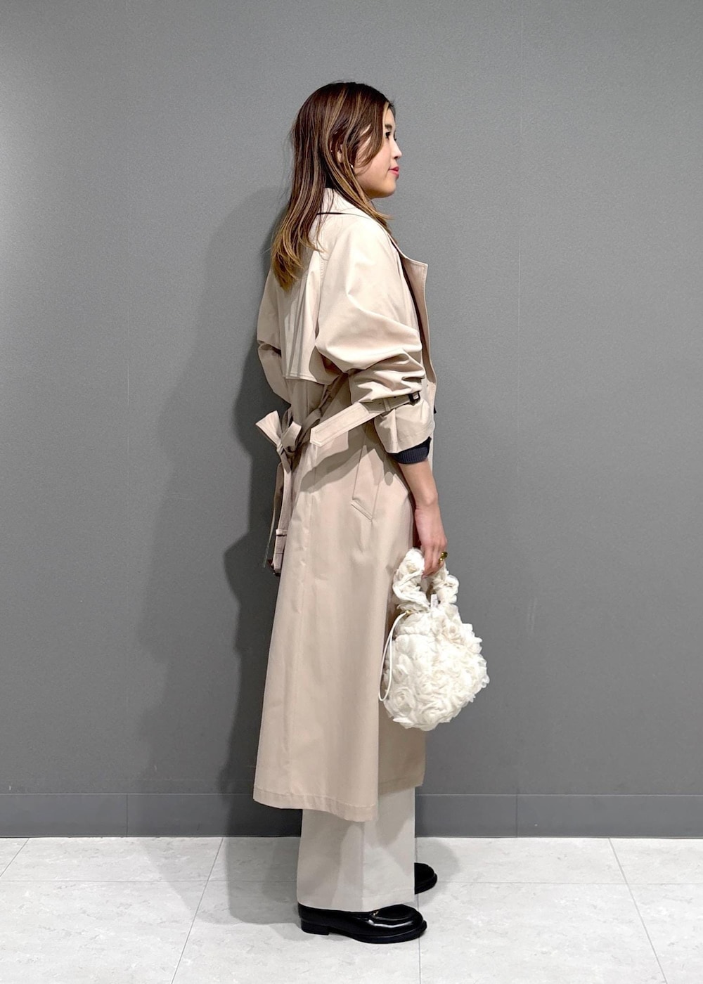 ブラック系のローファー、ブラック系のニット/セーター、ベージュ系のトレンチコートを着用したレディースの春コーディネートの2枚目の写真