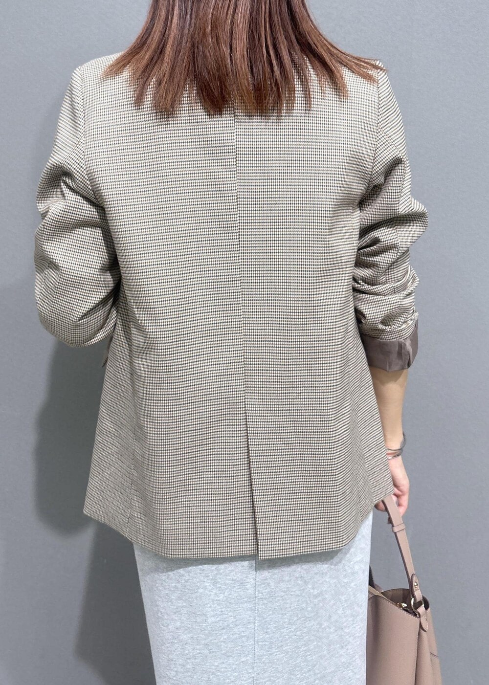 ベージュ系のテーラードジャケット、グレー系のスカート、ホワイト系のベストを着用したレディースの秋コーディネートの6枚目の写真