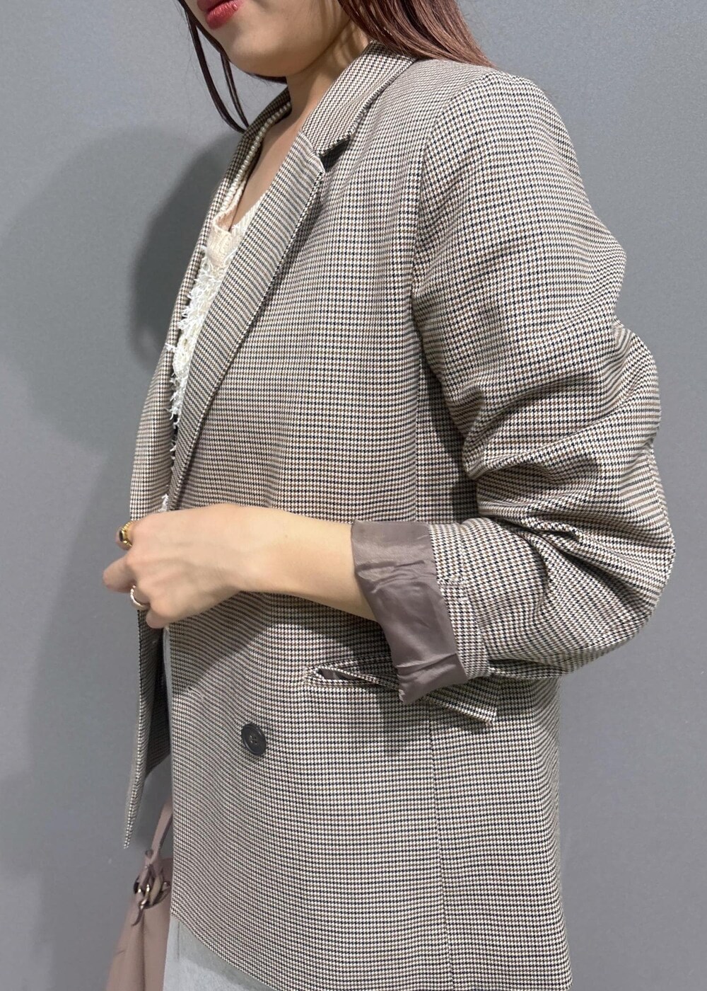 ベージュ系のテーラードジャケット、グレー系のスカート、ホワイト系のベストを着用したレディースの秋コーディネートの5枚目の写真