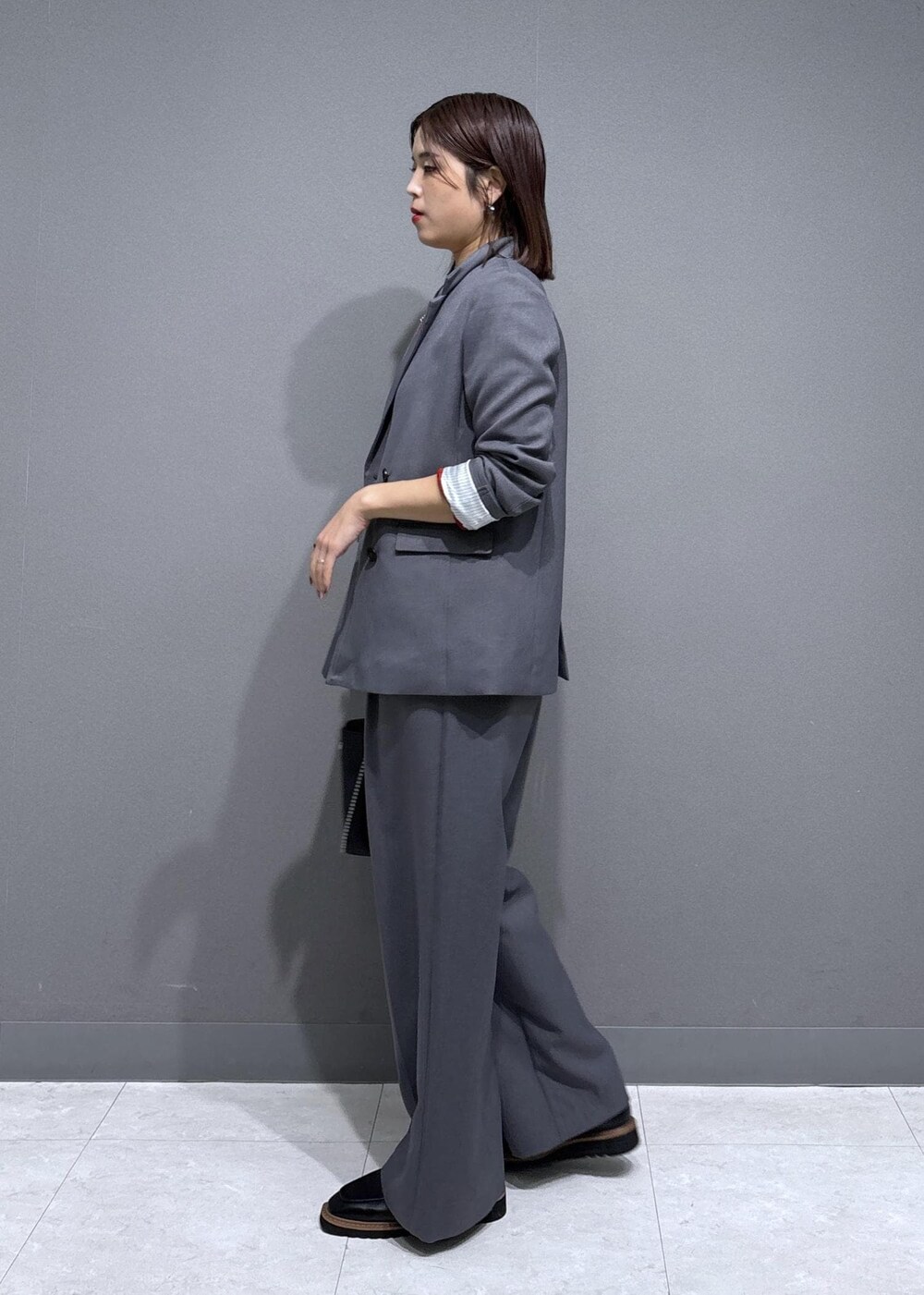 グレー系のスラックス、グレー系のテーラードジャケット、ブラック系のローファーを着用したレディースの秋コーディネートの2枚目の写真