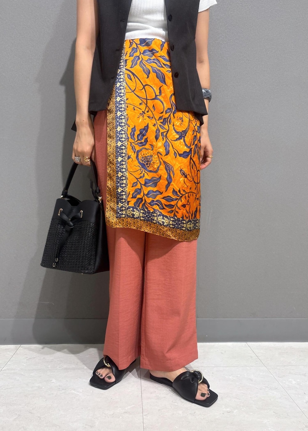 ブラック系のサンダル、ホワイト系のニット/セーター、オレンジ系のスラックスを着用したレディースの夏コーディネートの6枚目の写真